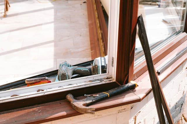 A hammer and drill on a window sill mid-repair