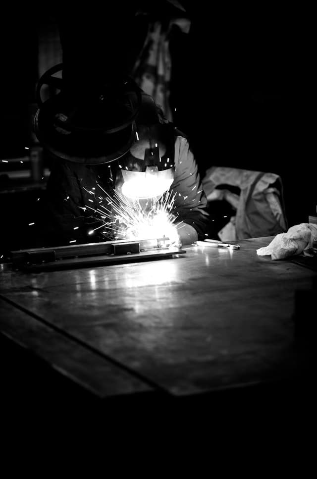 A welder working, sparks flying in the dark