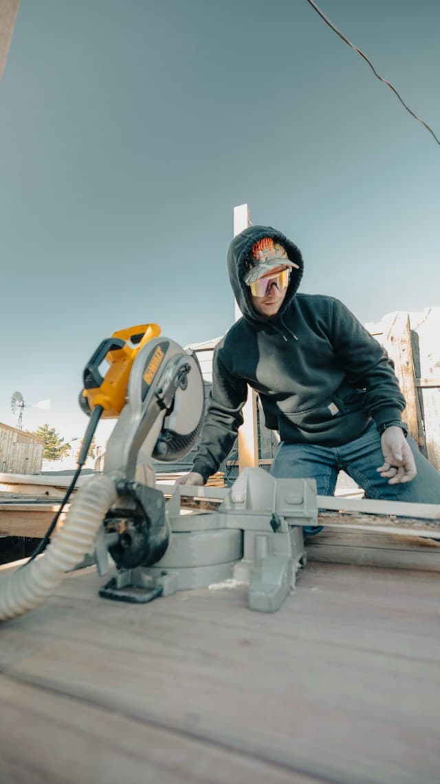 A tradie using a mitre saw on a timber deck
