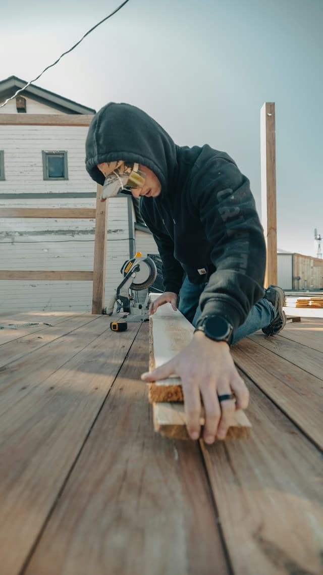 A tradie in safety glasses cutting timber with a saw